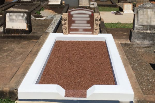 Single monument grave -  concrete surround with an 'ogee' front and granite footplate, painted white and steel grey, terracotta chips on floor, an Australian Calca headstone with a white incised inscription and Helidon Sandstone hand carved columns on either side. 